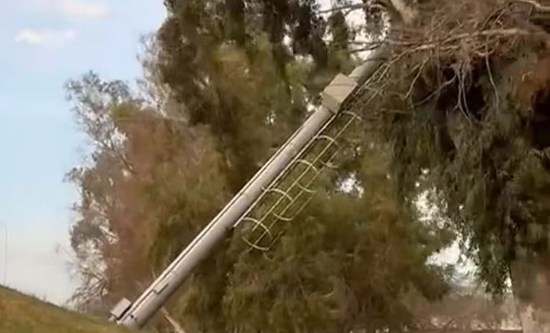 Un poste cae por el viento y queda suspendido en un árbol