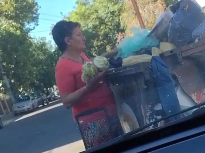 En plena ciudad de San Juan una mujer busca comida entre los residuos