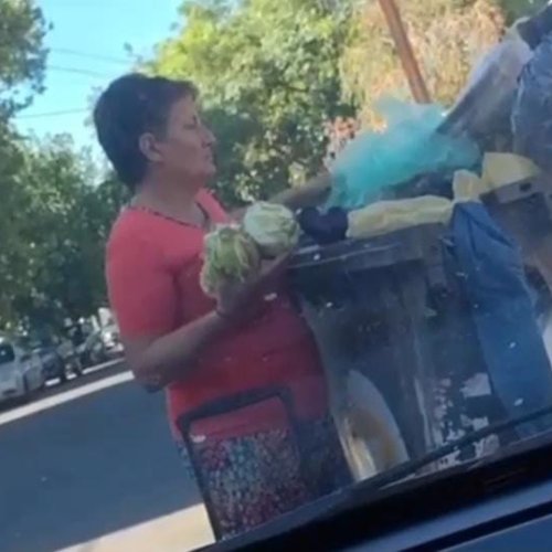 En plena ciudad de San Juan una mujer busca comida entre los residuos