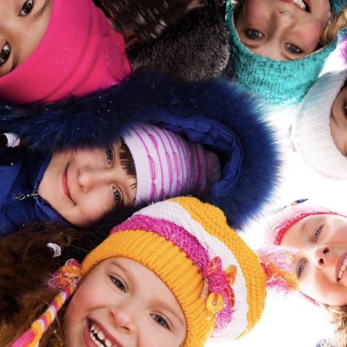 Group of happy kids look down wearing winter clothes