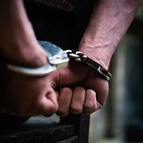 Man on the chair in Handcuffs. Rear view and Closeup ,Men criminal in handcuffs arrested for crimes. With hands in back,boy  prison shackle in the jail violence concept.